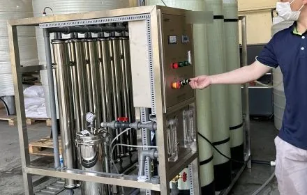 Technician operating the control panel of a compact treatment skid during inspection