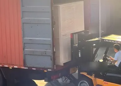 Crated water-treatment equipment being loaded into a shipping container by forklift